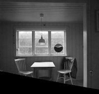Black and white room with table, chairs, window, and lamp