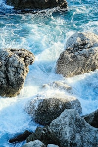 Turquoise ocean waves crash over sunlit rocks