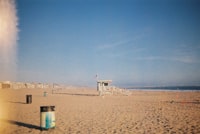 A wooden lifeguard tower on a sandy beach under a clear blue sky