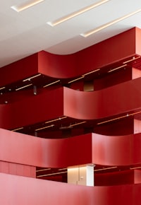 Curved red balconies in a modern building interior with recessed ceiling lighting